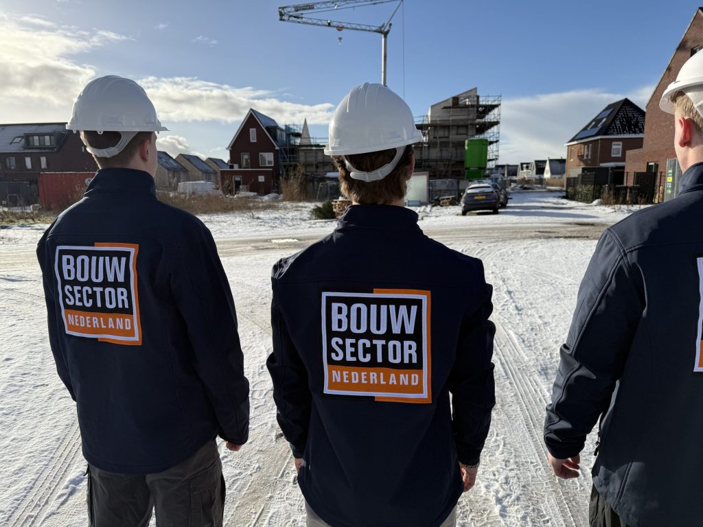 Drie vakmensen van Bouwsector Nederland met witte helm op een nieuwbouwlocatie in de sneeuw